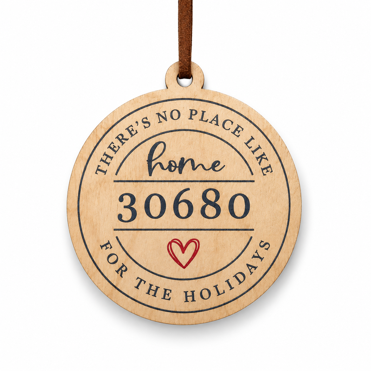 A round wooden ornament with a hanging loop, featuring the engraved text 'THERE'S NO PLACE LIKE home 30680 FOR THE HOLIDAYS' and a small red heart, shown on a white background.