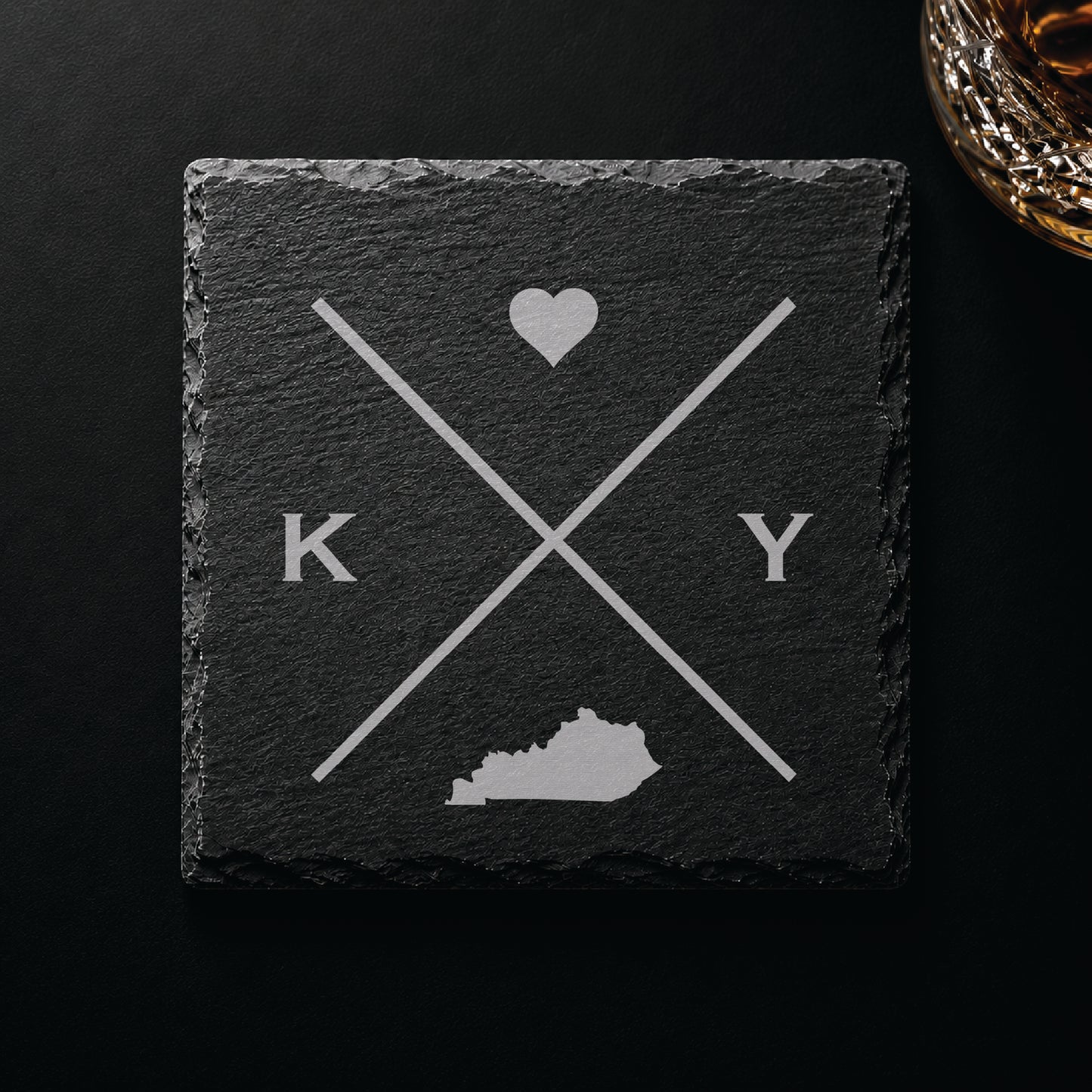 Dark slate coaster with engraved Kentucky crossed-line design, heart icon, and Kentucky silhouette on a dark background.