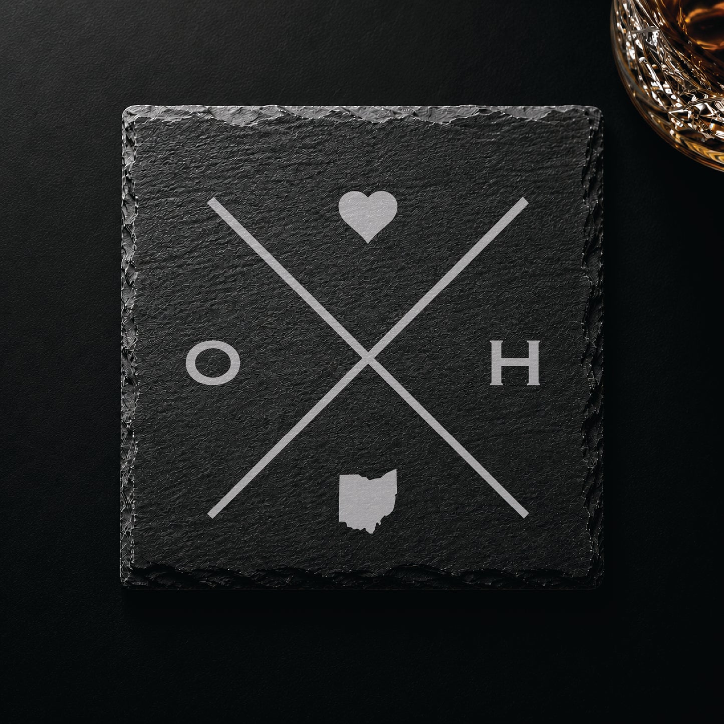 Dark slate coaster with engraved Ohio crossed-line design, heart icon, and Ohio silhouette on a dark background.