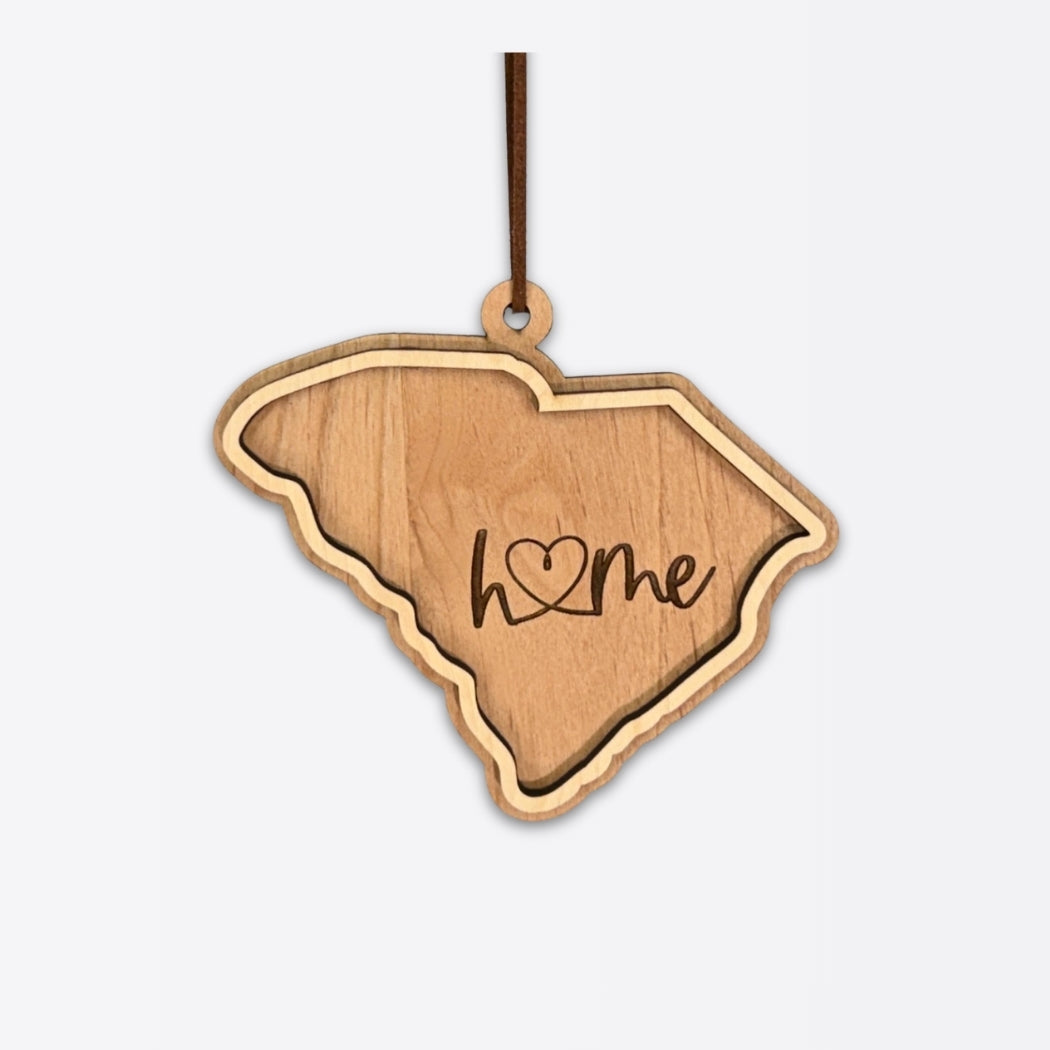 Layered South Carolina wood ornament with engraved “home” script and faux leather cord on a white background.