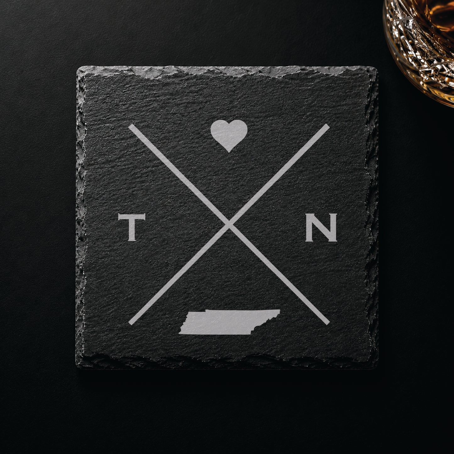 Dark slate coaster with engraved Tennessee crossed-line design, heart icon, and Tennessee silhouette on a dark background.