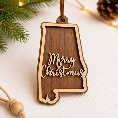 Wooden ornament shaped like the state of Alabama with 'Merry Christmas' text, surrounded by Christmas decorations.