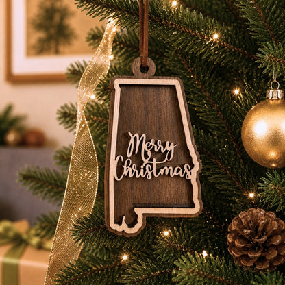 Wooden 'Merry Christmas' ornament shaped like the state of Alabama hanging on a decorated Christmas tree.