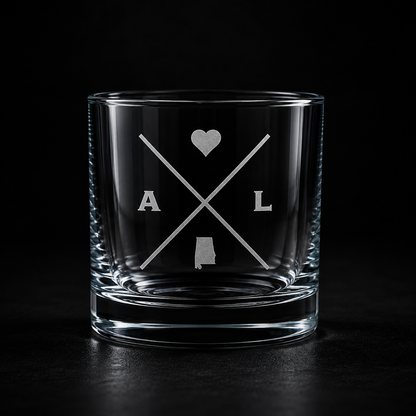 Engraved Alabama rocks glass with frosted Alabama silhouette and crossed-letter monogram on a dark background.