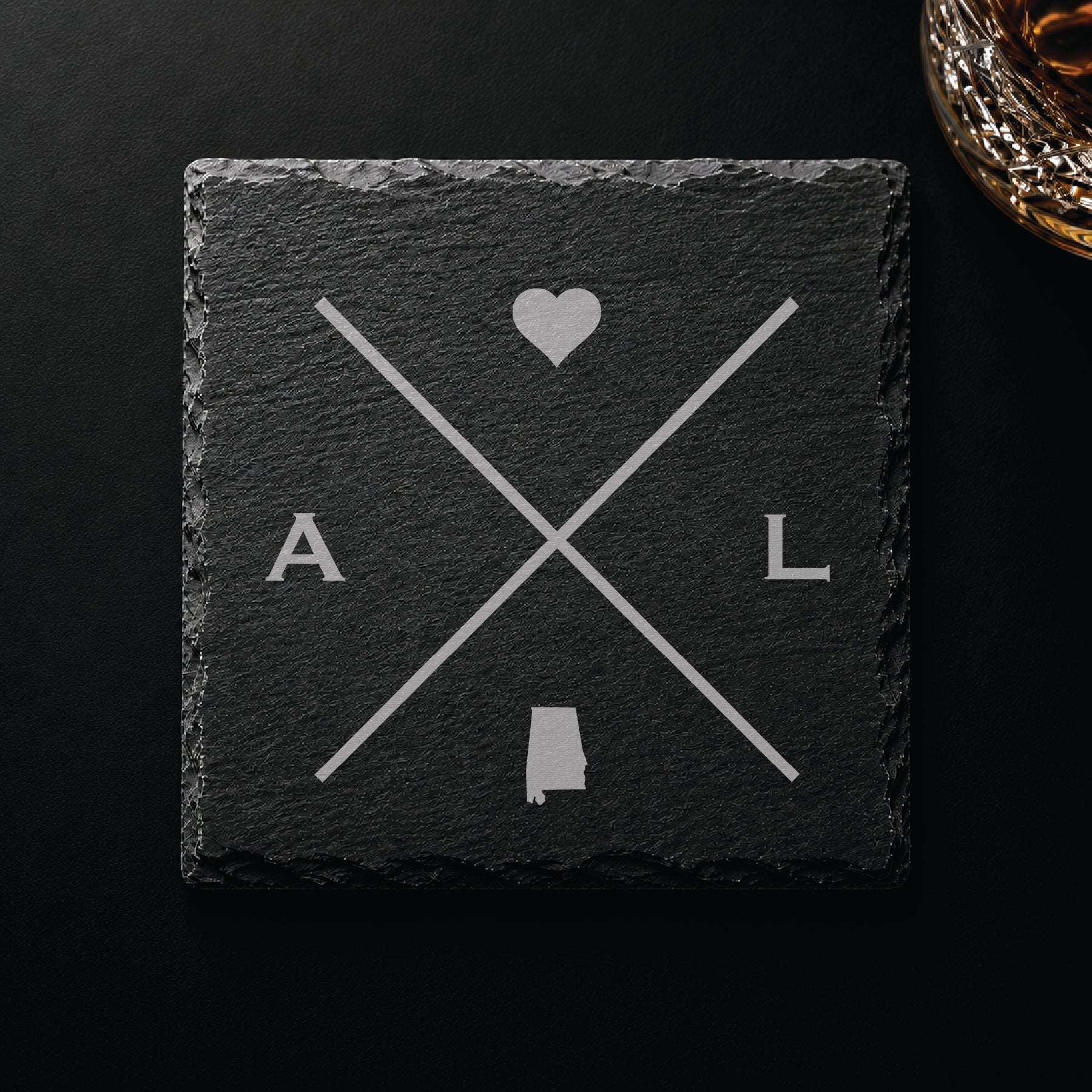 Dark slate coaster with engraved Alabama crossed-line design, heart icon, and Alabama silhouette on a dark background.