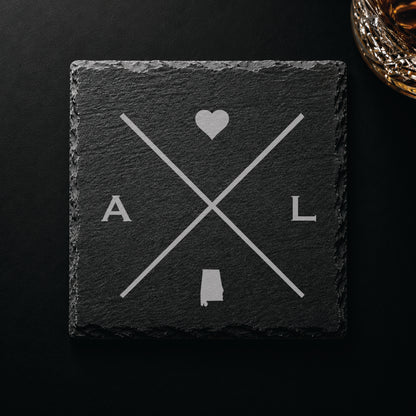 Dark slate coaster with engraved Alabama crossed-line design, heart icon, and Alabama silhouette on a dark background.