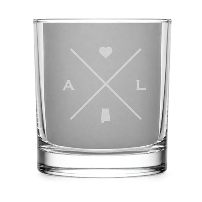 Clear engraved rocks glass featuring a minimalist crossed-line Alabama design with monogram initials, heart icon, and Alabama silhouette on a clean light background.