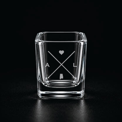 Engraved Alabama shot glass with modern crossed-line state design and frosted laser engraving on a dark background.
