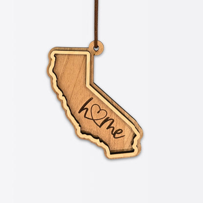 Layered California wood ornament with engraved “home” script and faux leather cord on white background.
