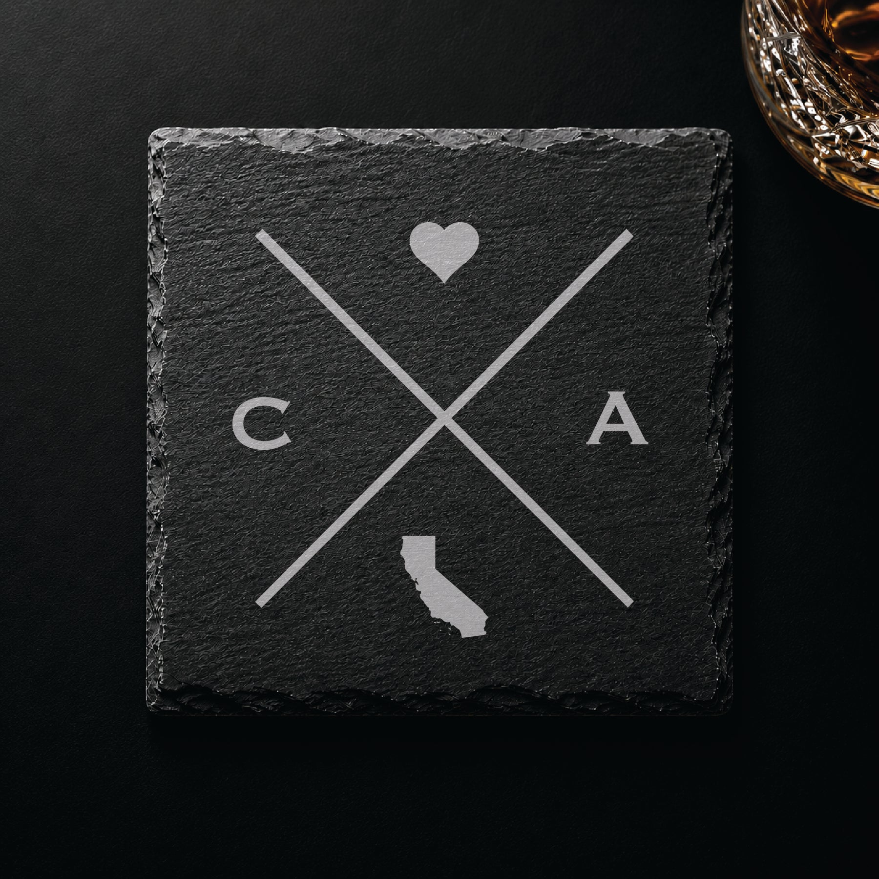 Engraved California slate coaster featuring a minimalist crossed-line design with heart detail and California silhouette on a clean light background.