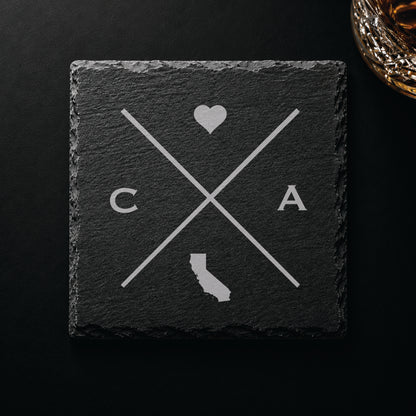 Engraved California slate coaster featuring a minimalist crossed-line design with heart detail and California silhouette on a clean light background.