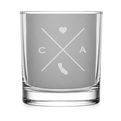 Clear engraved rocks glass featuring a minimalist crossed-line California design with monogram initials, heart icon, and California silhouette on a clean light background.