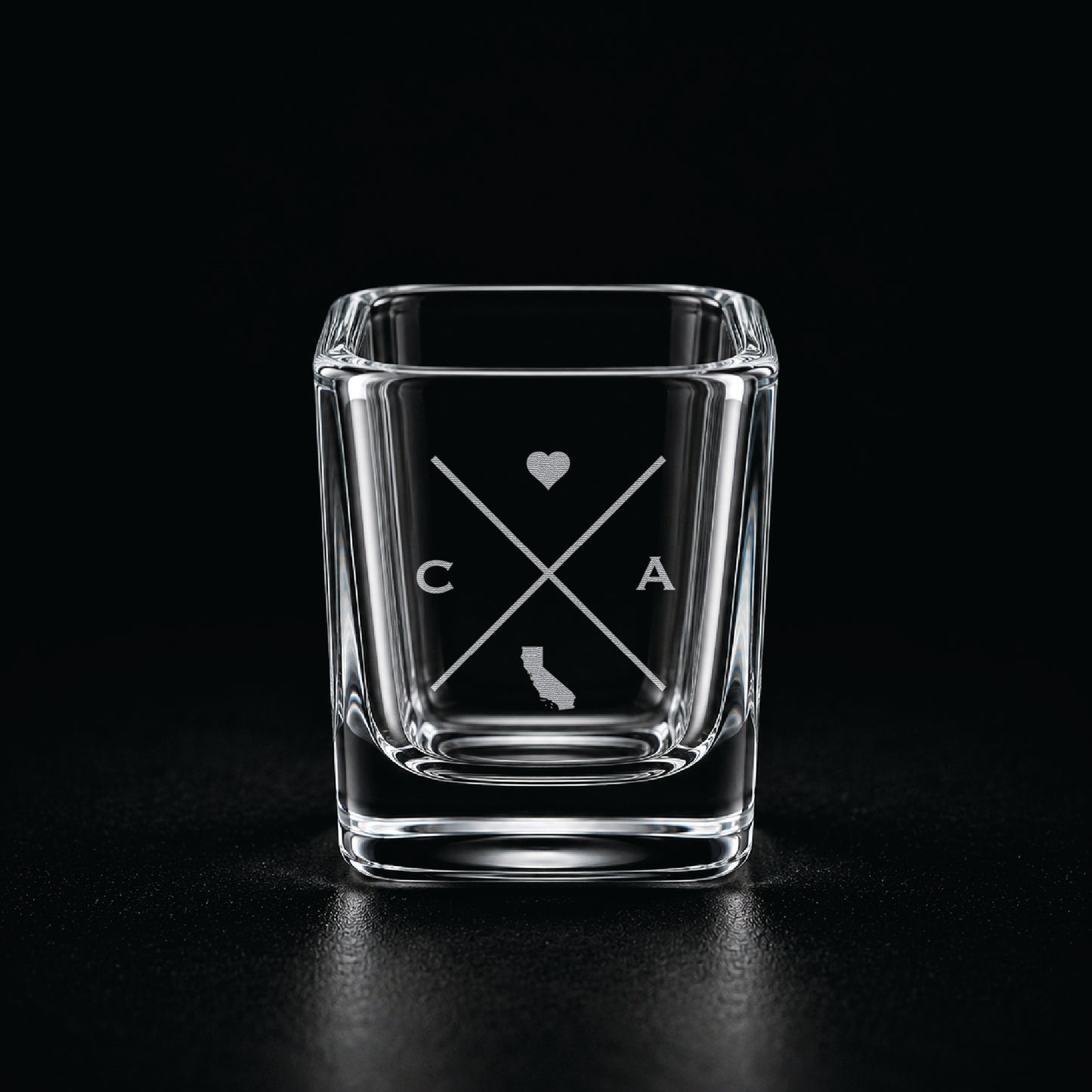 Engraved California shot glass with modern crossed-line state design and frosted laser engraving on a dark background.