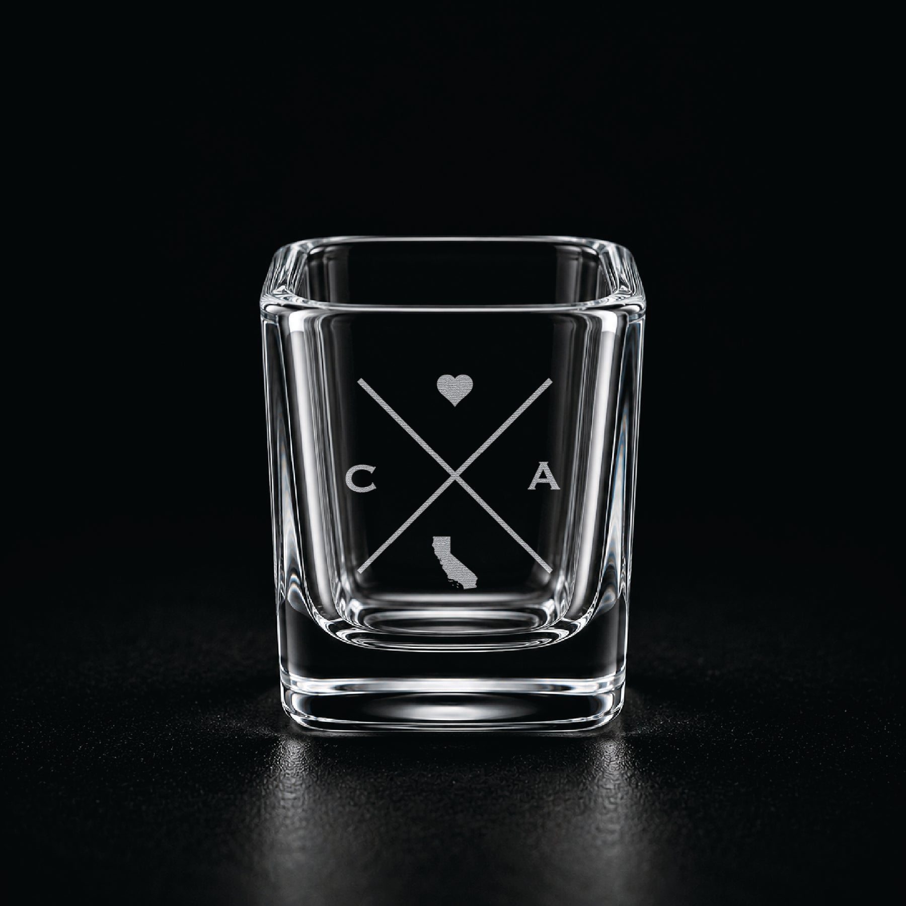 Engraved California shot glass with modern crossed-line state design and frosted laser engraving on a dark background.