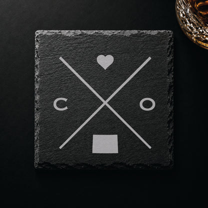 Engraved Colorado slate coaster featuring a minimalist crossed-line design with heart detail and Colorado silhouette on a clean light background.