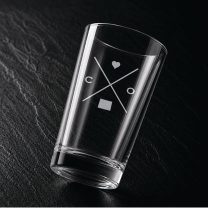 Angled view of engraved Colorado pint glass with modern crossed-line state design and frosted laser engraving on dark textured surface.