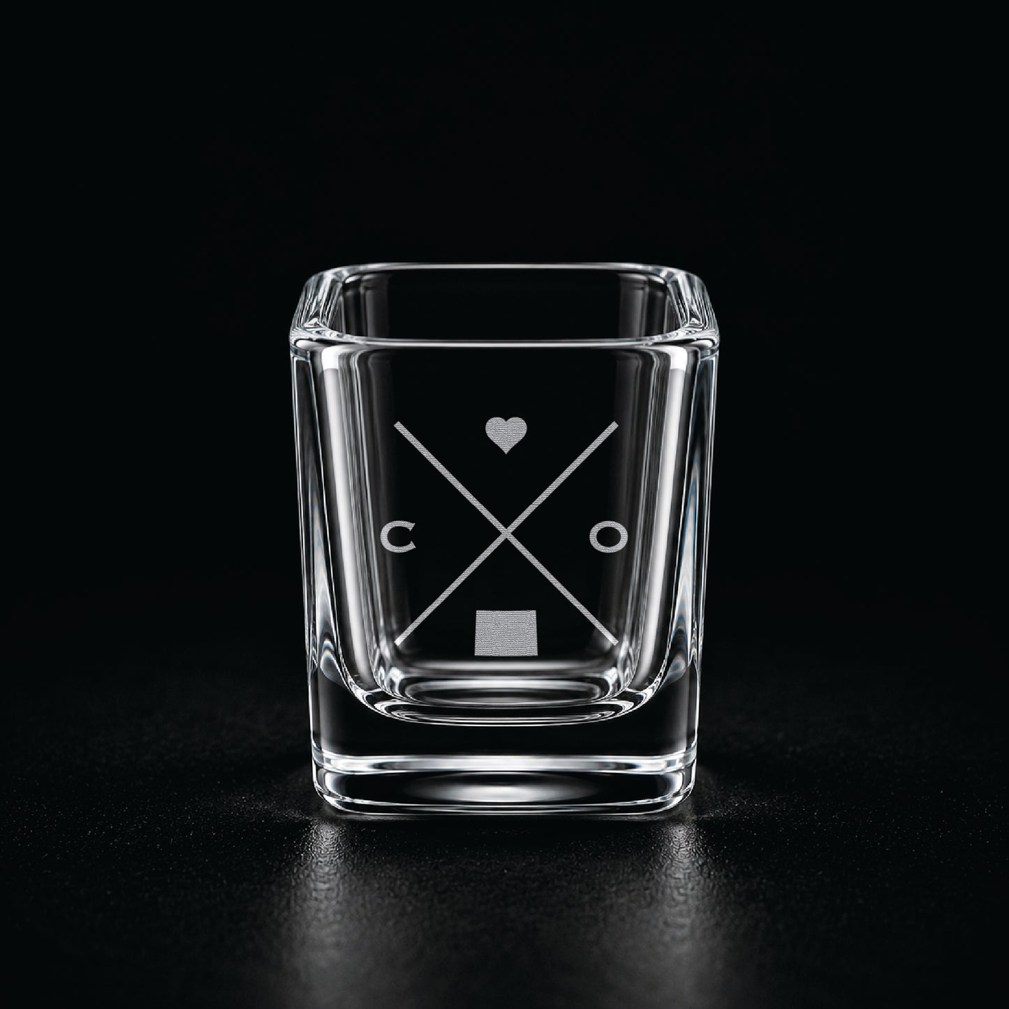 Engraved Colorado shot glass with modern crossed-line state design and frosted laser engraving on a dark background.