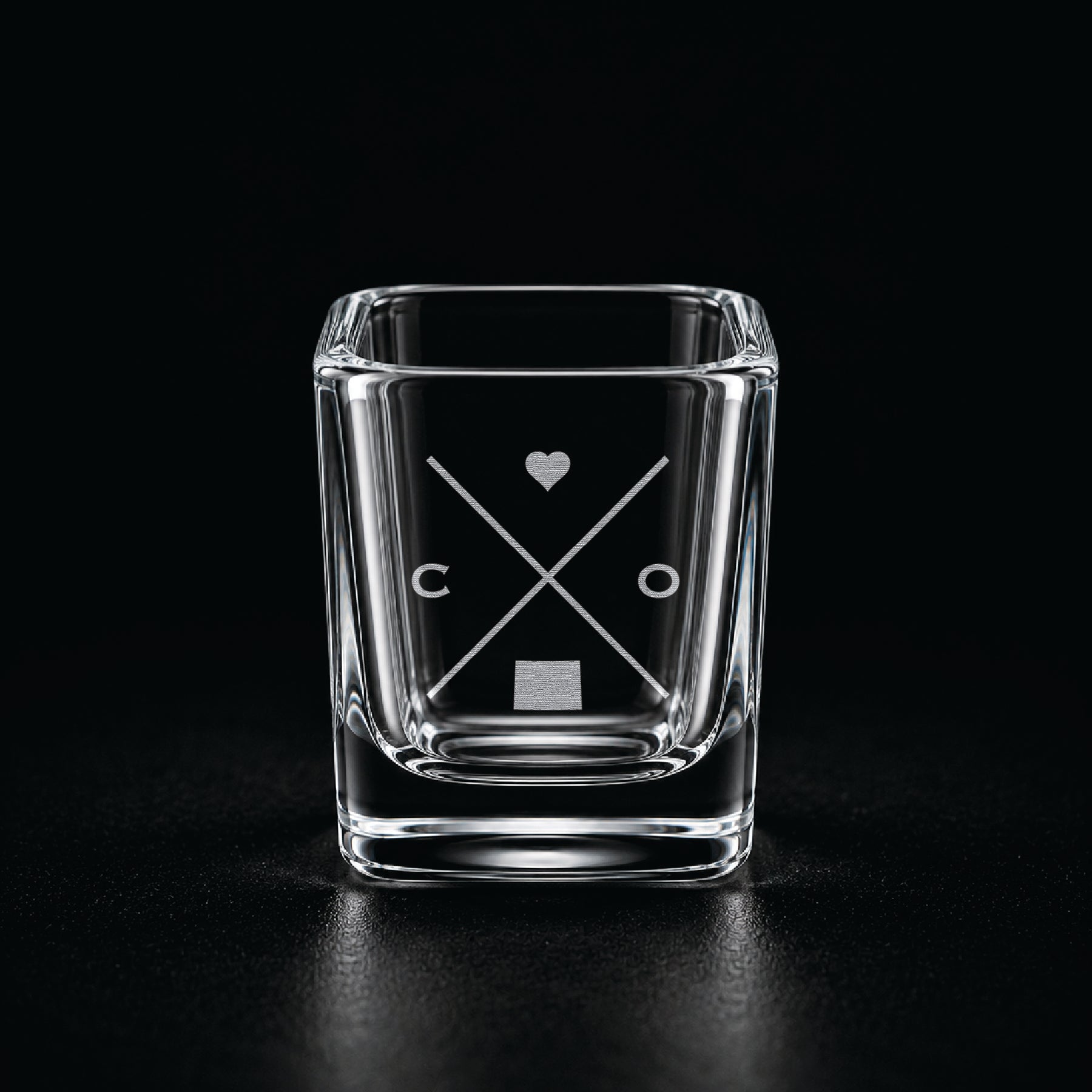 Engraved Colorado shot glass with modern crossed-line state design and frosted laser engraving on a dark background.