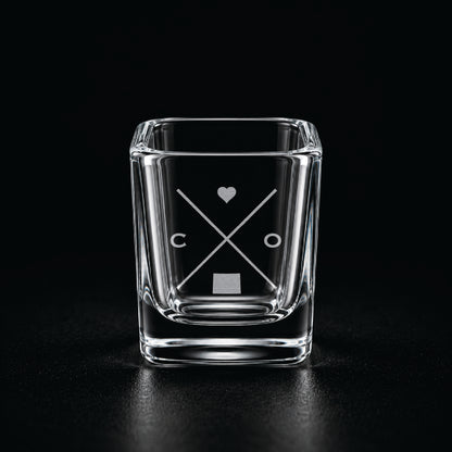 Engraved Colorado shot glass with modern crossed-line state design and frosted laser engraving on a dark background.