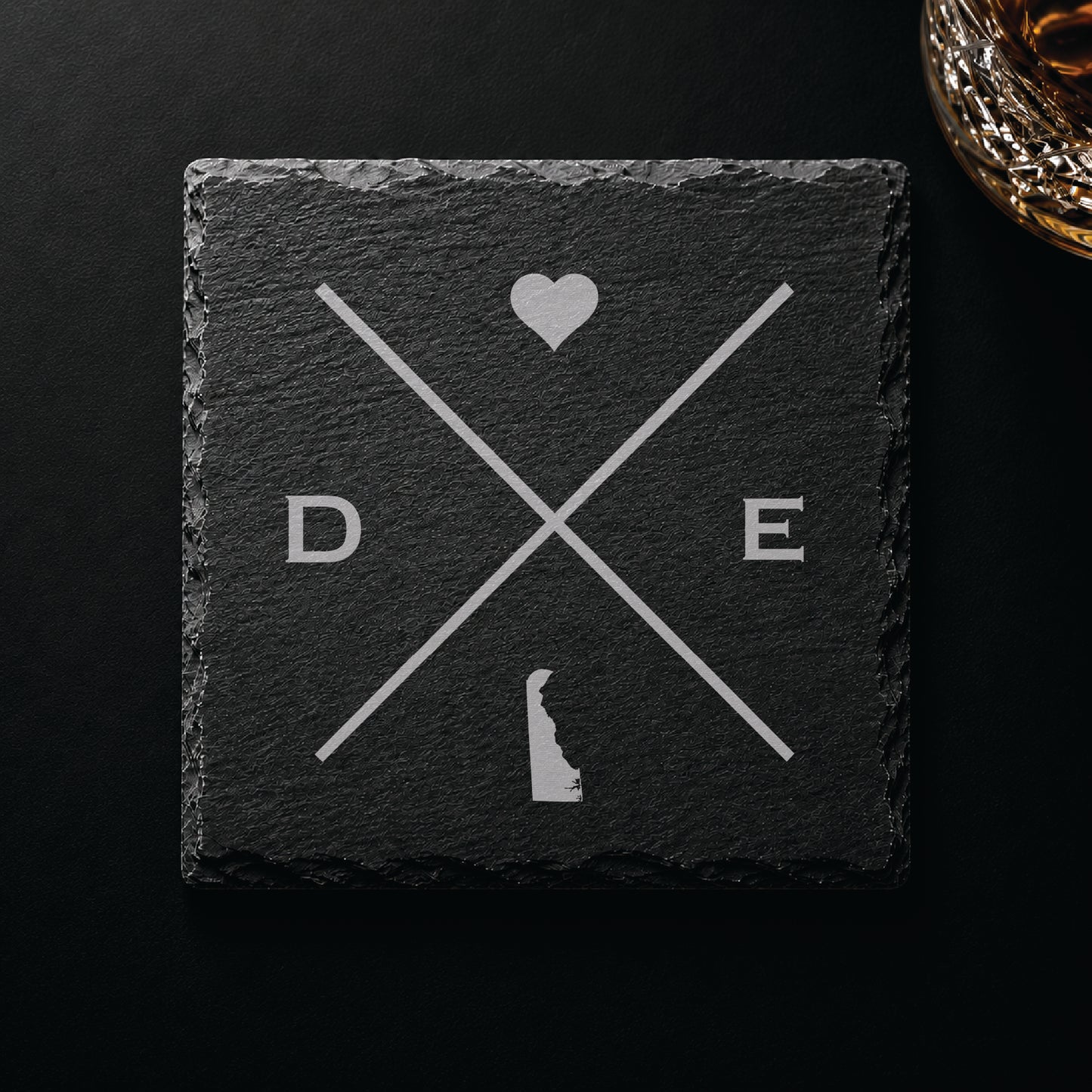 Dark slate coaster with engraved Delaware crossed-line design, heart icon, and Delaware silhouette on a dark background.