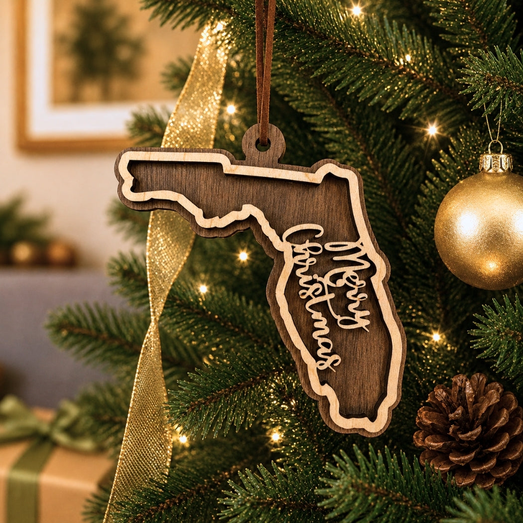 Wooden ornament shaped like Florida with 'Merry Christmas' text, hanging on a decorated Christmas tree.