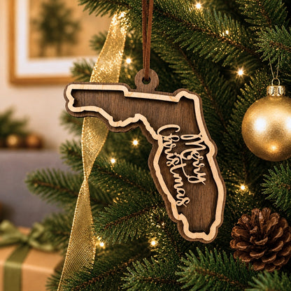 Wooden ornament shaped like Florida with 'Merry Christmas' text, hanging on a decorated Christmas tree.