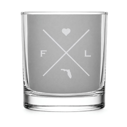 Clear engraved rocks glass featuring a minimalist crossed-line Florida design with monogram initials, heart icon, and Florida silhouette on a clean light background.