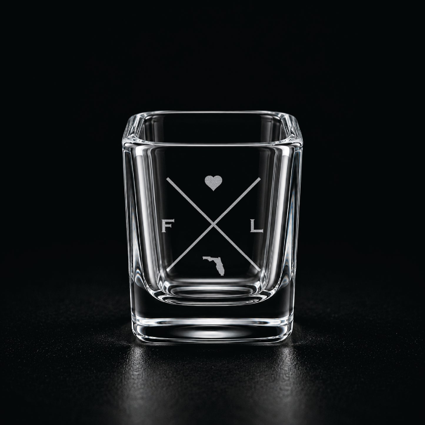 Engraved Florida shot glass with modern crossed-line state design and frosted laser engraving on a dark background.