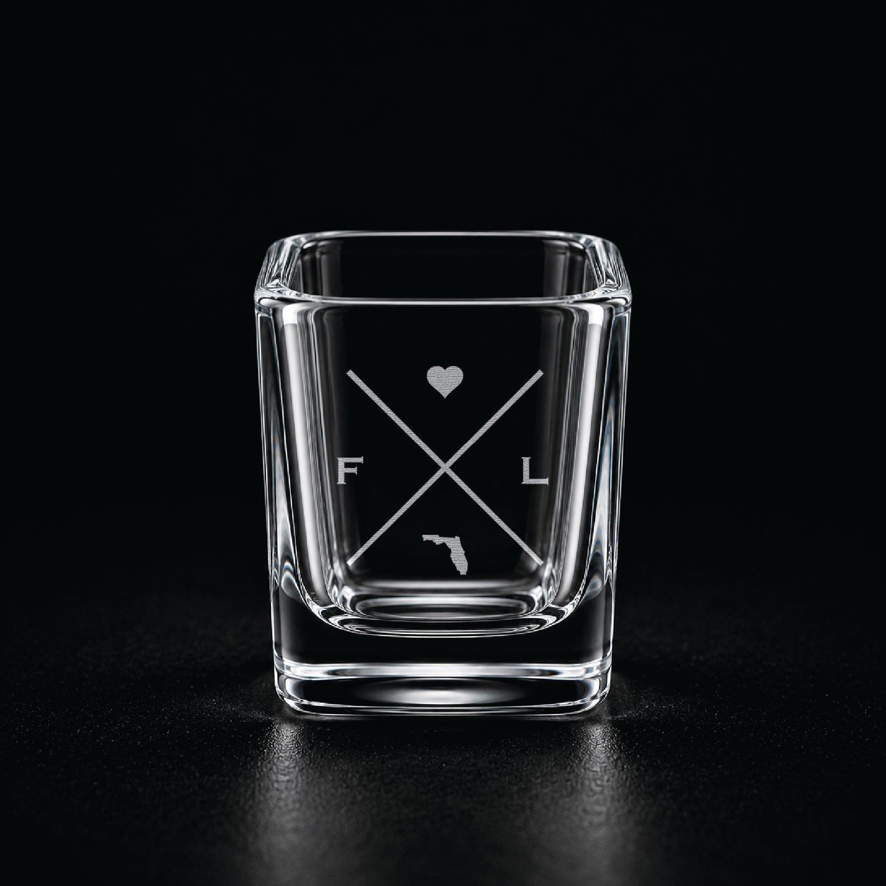 Engraved Florida shot glass with modern crossed-line state design and frosted laser engraving on a dark background.