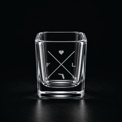 Engraved Florida shot glass with modern crossed-line state design and frosted laser engraving on a dark background.