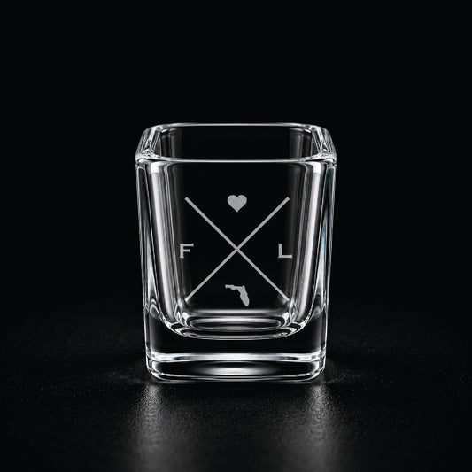 Engraved Florida shot glass with modern crossed-line state design and frosted laser engraving on a dark background.