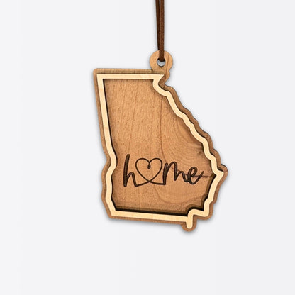 Layered Georgia wood ornament with engraved “home” script and faux leather cord on white background.