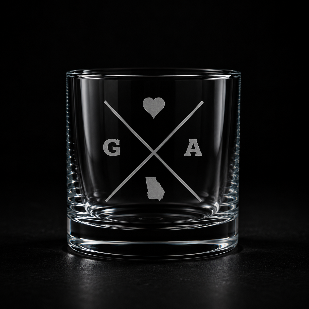 Engraved Georgia rocks glass with frosted Georgia silhouette and crossed-letter monogram on a dark background.
