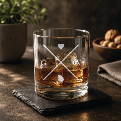 Engraved Georgia rocks glass with crossed-line monogram design, heart detail, and Georgia state silhouette, styled with whiskey and ice on a slate coaster in a warm, upscale bar setting.