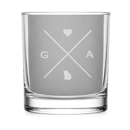 Clear engraved rocks glass featuring a minimalist crossed-line Georgia design with monogram initials, heart icon, and Georgia silhouette on a clean light background.