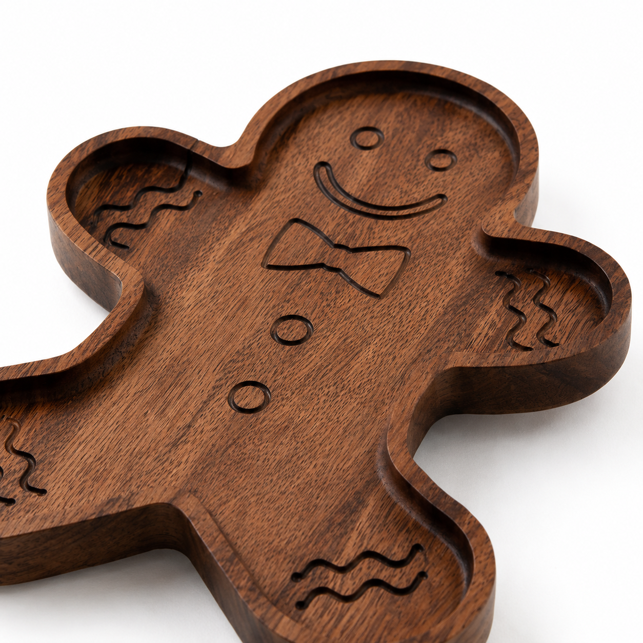 Angled close-up of a gingerbread snack tray showing carved details, rounded recessed edges, and natural wood grain on a clean light background.