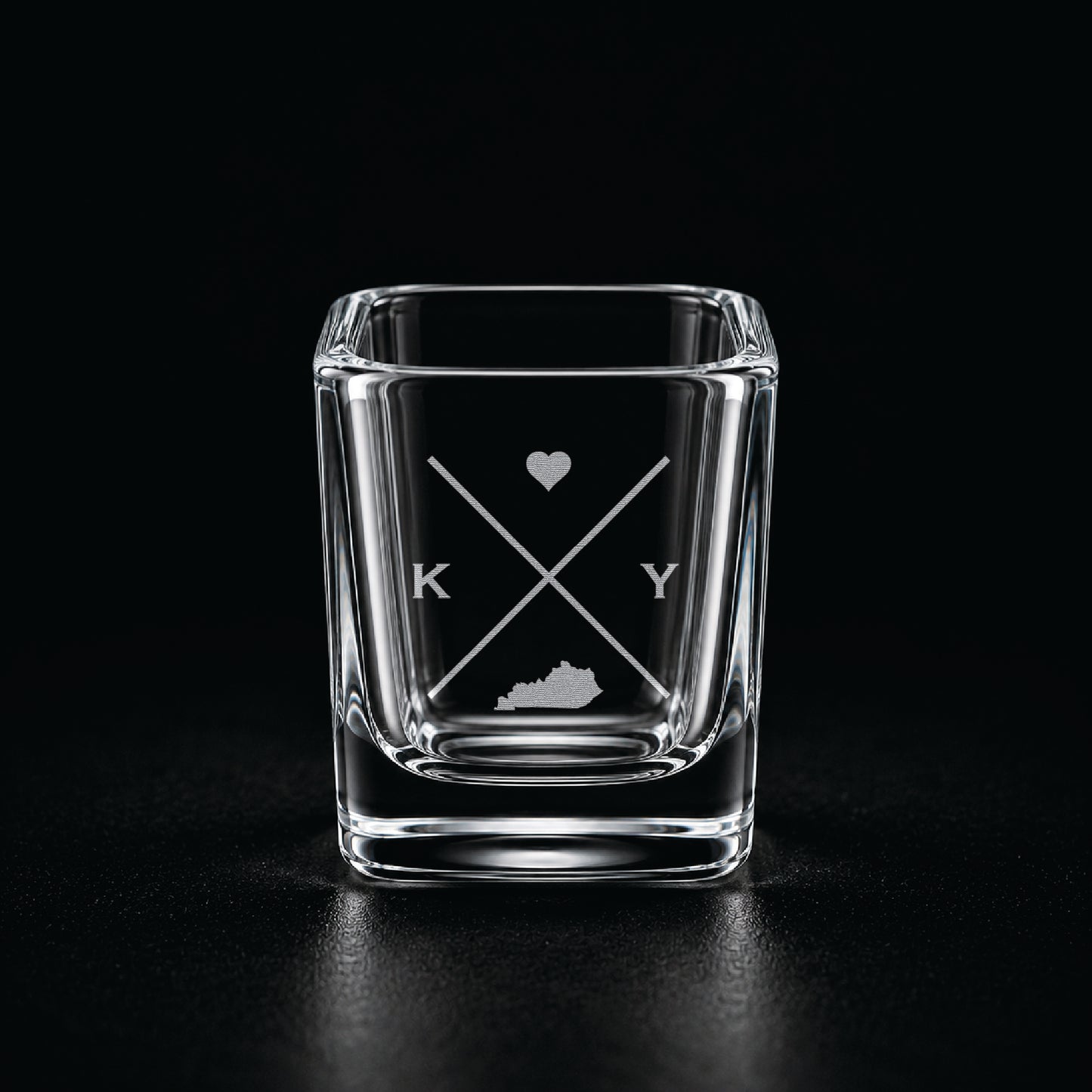 Engraved Kentucky shot glass with modern crossed-line state design and frosted laser engraving on a dark background.