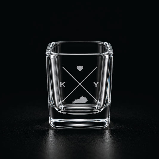 Engraved Kentucky shot glass with modern crossed-line state design and frosted laser engraving on a dark background.