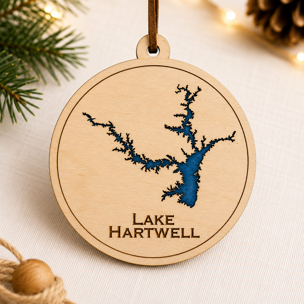 Close-up angled view of layered wood Lake Hartwell ornament showing dimensional lake design and engraved lettering.