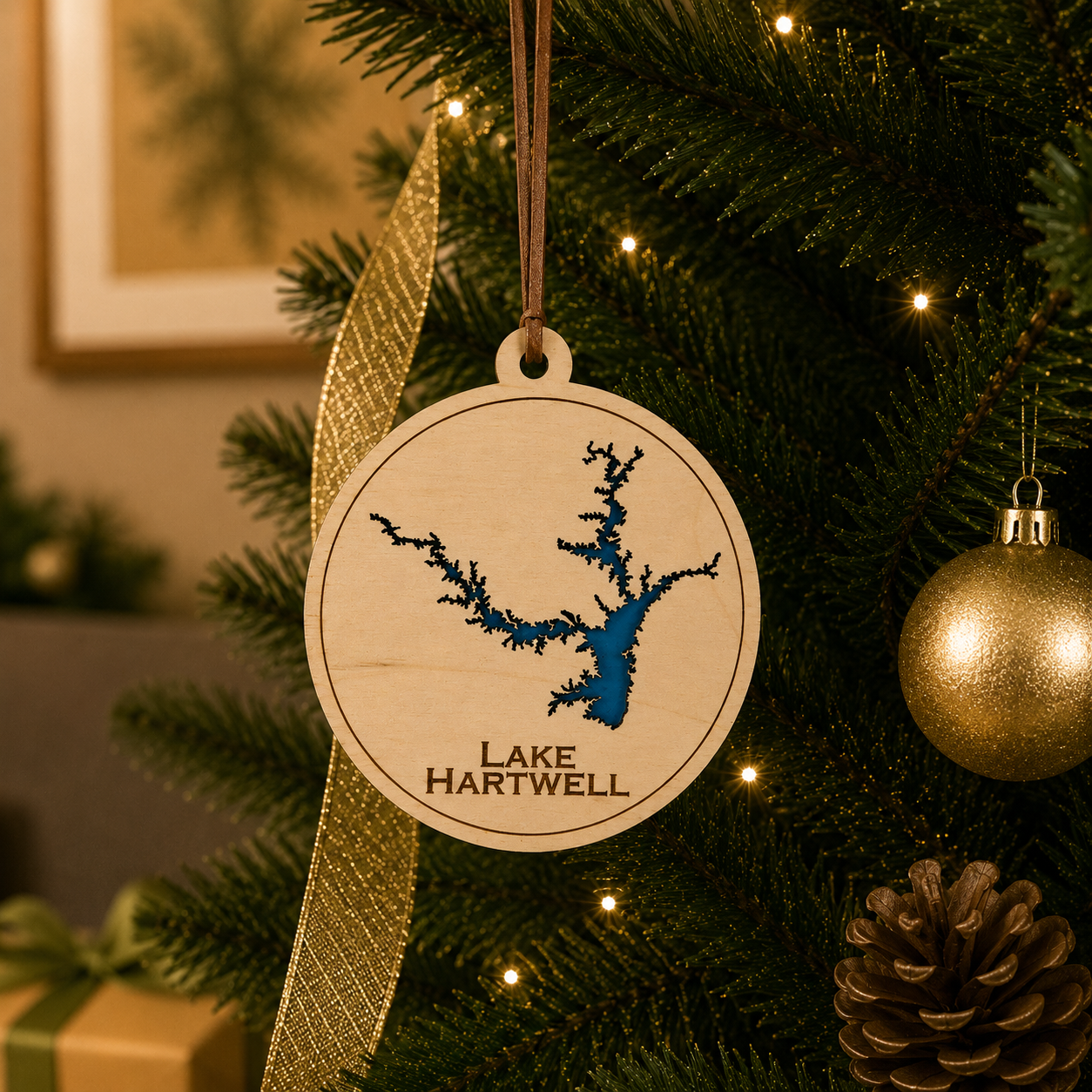 Layered wood Lake Hartwell ornament hanging on a decorated Christmas tree with warm lights and gold ribbon.