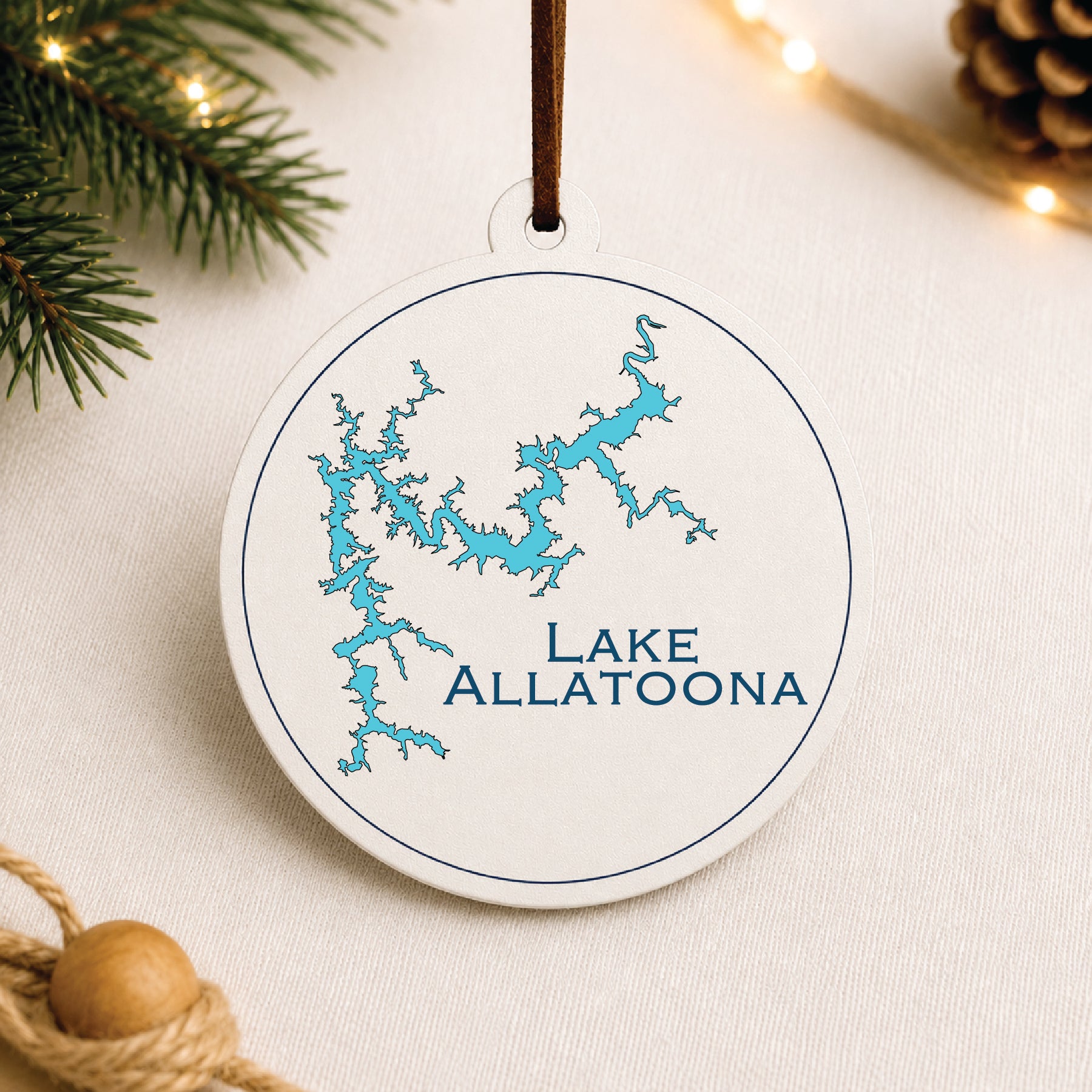 White Lake Allatoona ornament with blue lake map design on a warm holiday linen background with greenery and lights.