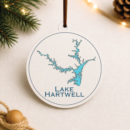 White Lake Hartwell ornament with blue lake map design on a warm holiday linen background with greenery and lights.