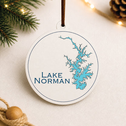 White Lake Norman ornament with blue lake map design on a warm holiday linen background with greenery and lights.