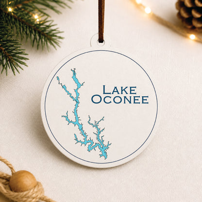 White Lake Oconee ornament with blue lake map design on a warm holiday linen background with greenery and lights.