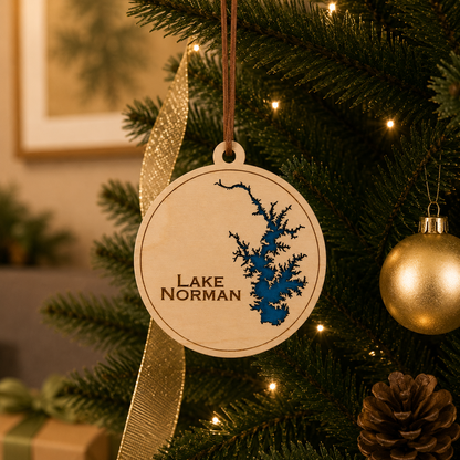 Layered wood Lake Norman ornament hanging on a decorated Christmas tree with warm lights and gold ribbon.