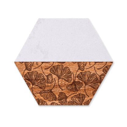 Hexagon marble and acacia wood coaster with engraved botanical leaf design on a white background.