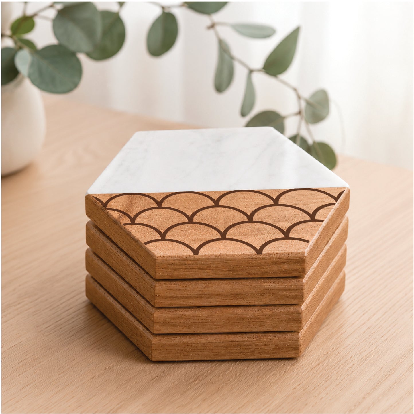 Scallop Pattern faux marble and acacia wood hexagon coaster set displayed on a light wood tabletop with soft natural décor and eucalyptus accents.