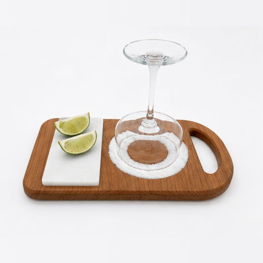 Cherry wood and marble margarita rimmer with lime wedges and margarita glass on white background.