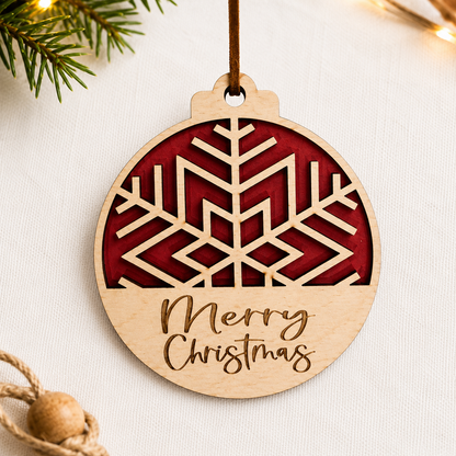 Layered wooden snowflake Christmas ornament with red backing and engraved Merry Christmas text styled on neutral fabric background