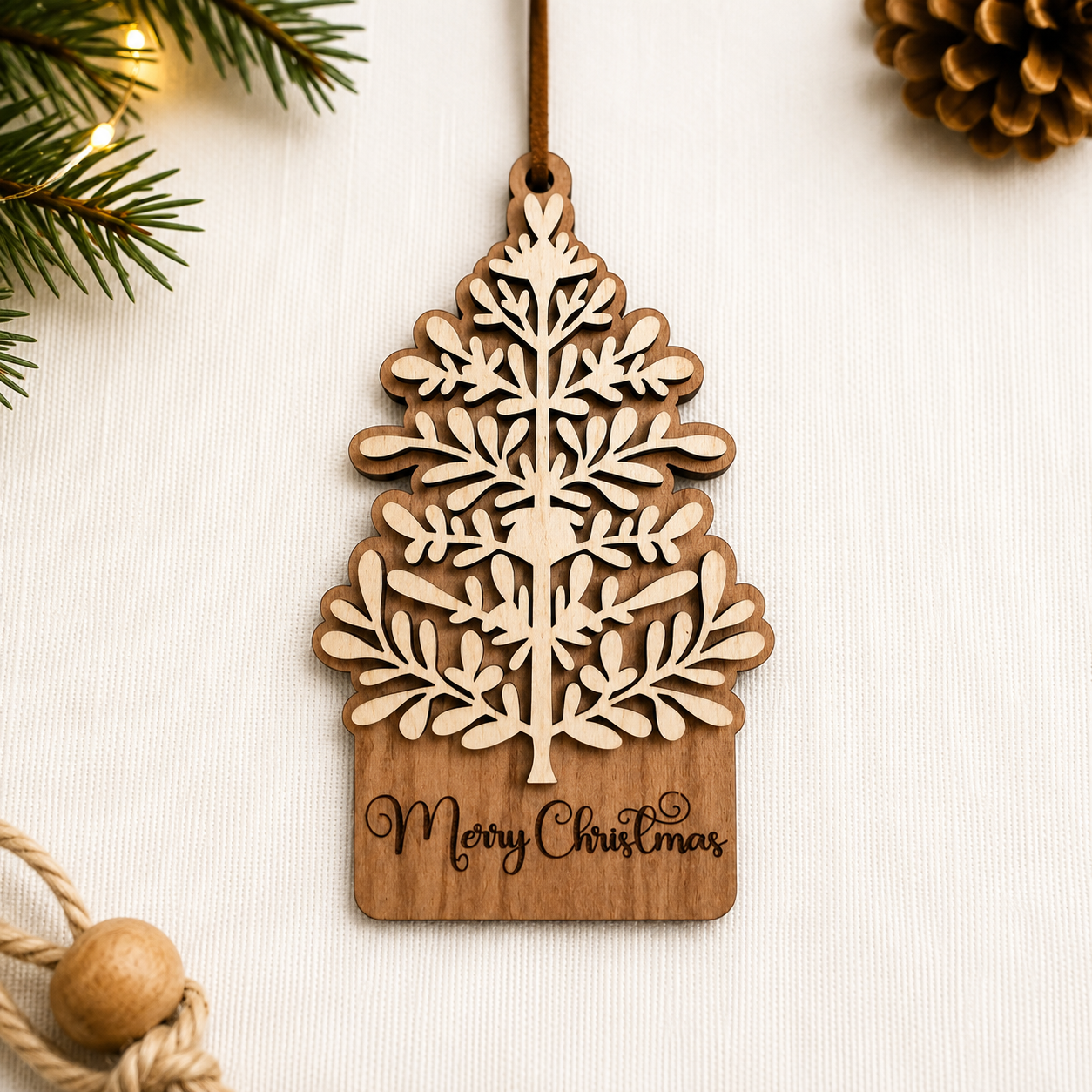 Cherry wood and maple layered Christmas tree ornament displayed on neutral fabric background